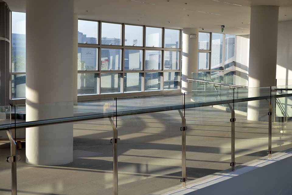 Commercial glass fence railing with stainless posts in a bright atrium