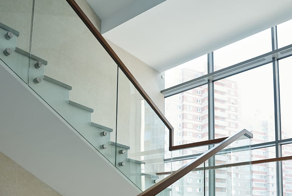 Point-supported commercial glass stair railing with a dark handrail